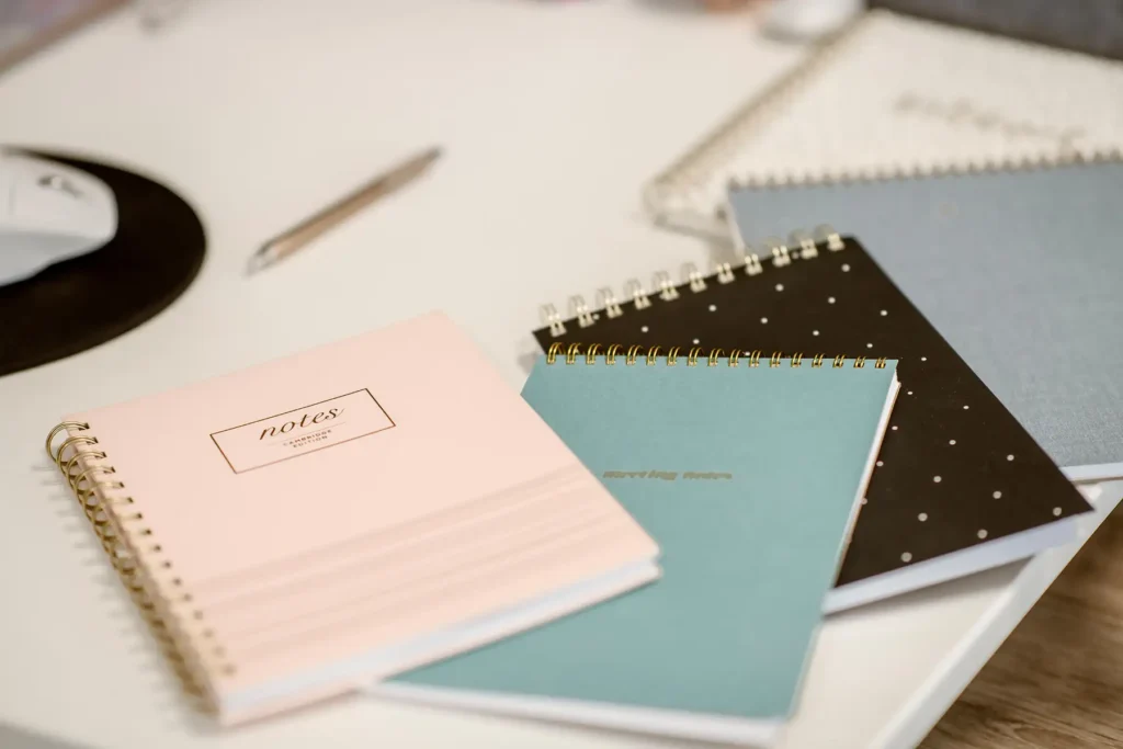 Three closed notebooks laid on a desk.