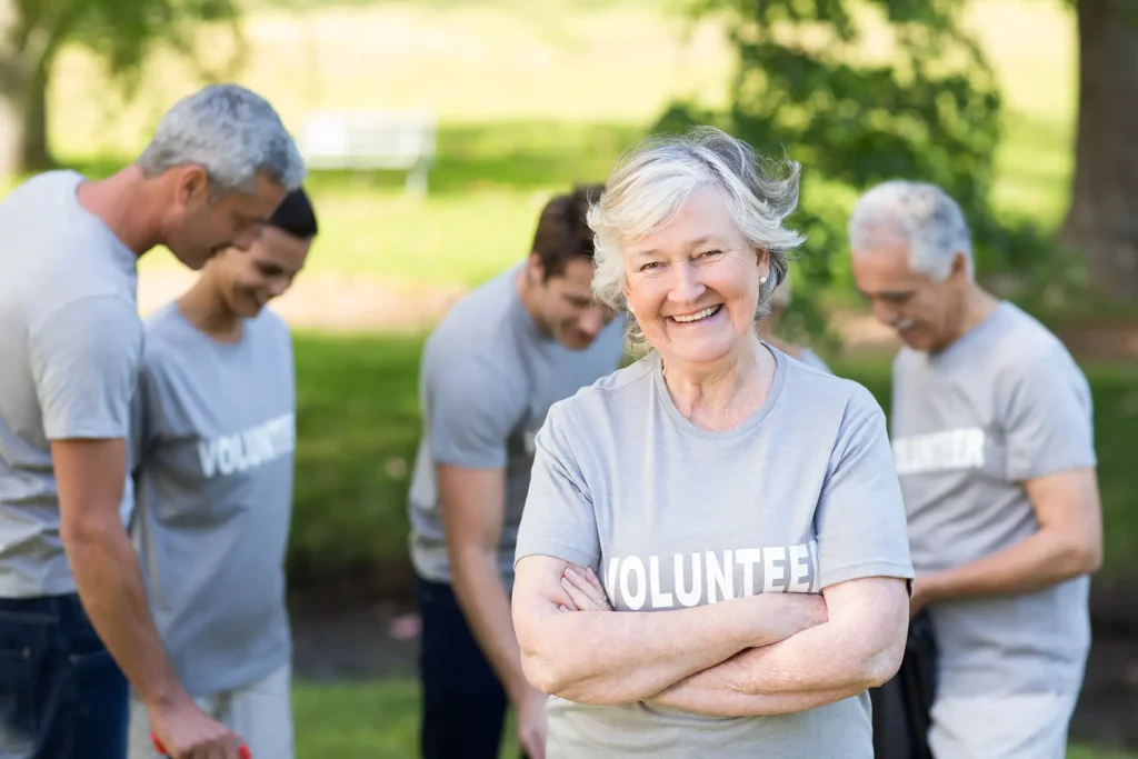 Woman wearing tshirt that says "Volunteer," posing at camera, with others behind her in the same t shirt