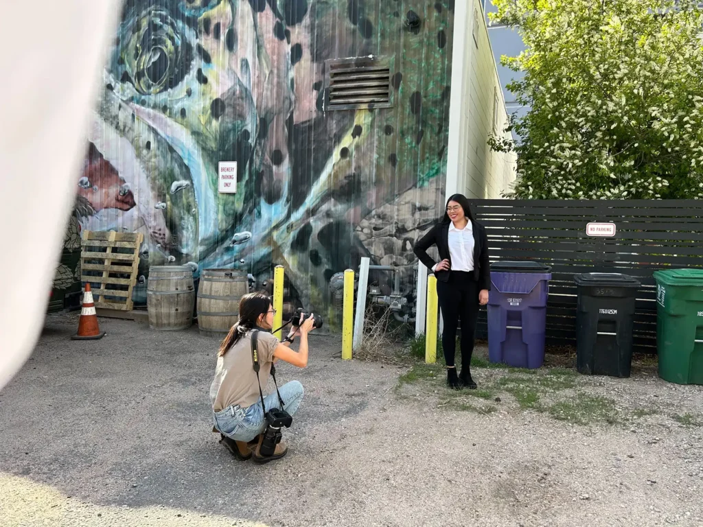 A photographer takes a picture of a woman in front of an outdoor mural