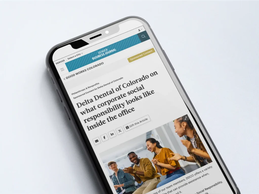 A phone with an article pulled up of "Delta Dental of Colorado on what corporate social responsibility looks like inside the office"