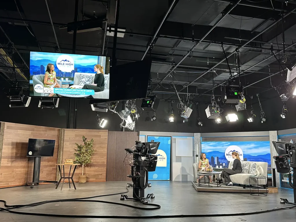 A reporter interviews a representative from Colorado Cancer Coalition in the studio.