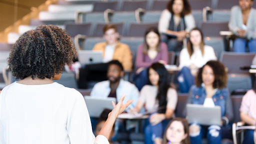 A woman stands in front of a lecture hall and gives a presentation