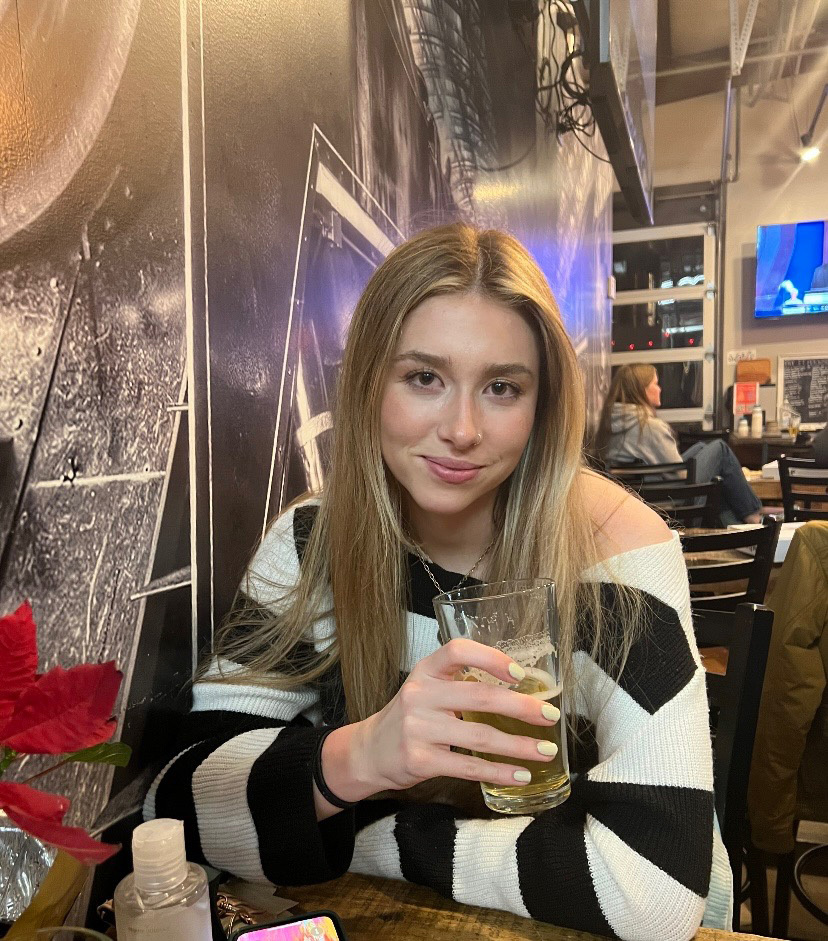 Annabelle sitting at a restaurant holding a glass of beer