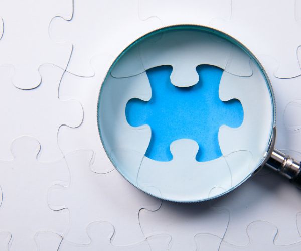 A magnifying glass looking at a missing puzzle piece