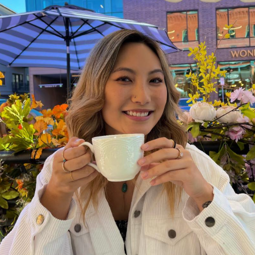 Hallie smiling while holding a white mug