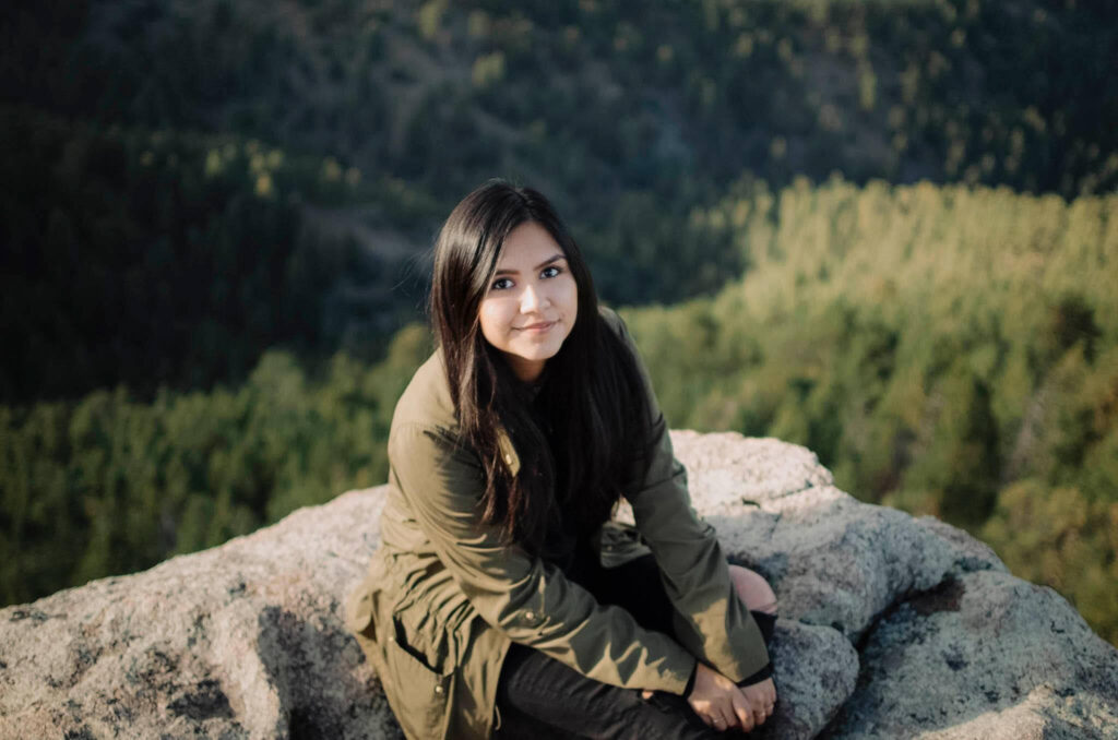Nadia sitting on a rock at the top of a cliff